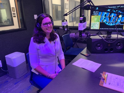 UTA President Jennifer Cowley participates in a live recording at the UTA Radio studio. She is wearing a headset and speaking into a professional microphone, engaging directly with student broadcasters