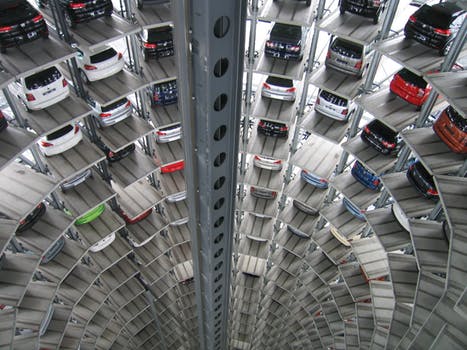 Tower-shaped cylindrical showroom with hundreds of cars neatly stacked across multiple floors