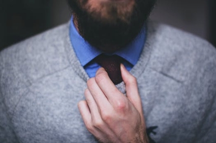 A man in professional attire, fixing his tie
