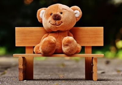 A smiling teddy sitting on a bench