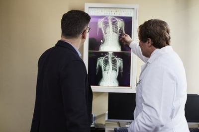 A doctor points to an X-ray while explaining it to another person