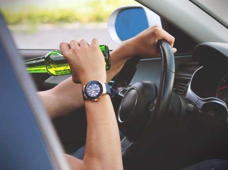 A person sipping from a drink bottle while driving a car