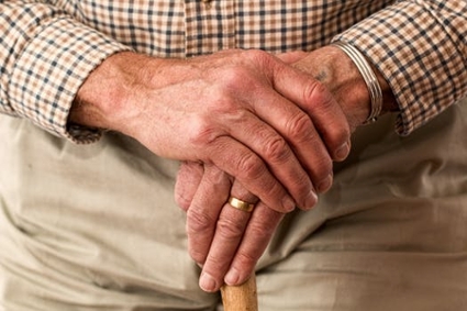 Wrinkled hands of an older man folded together