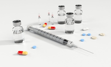 A syringe, vials of medicine and tablets arranged together