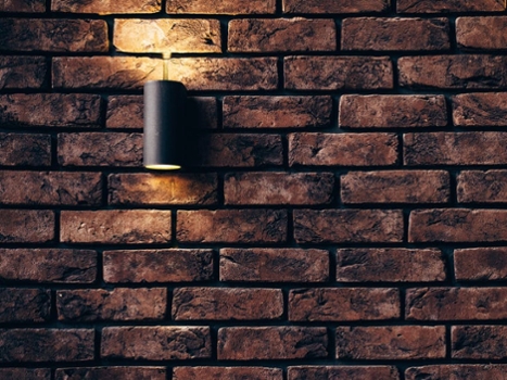 A modern lamp mounted on a stone-textured wall