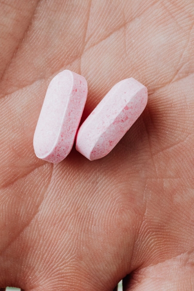 Two pink pills on the palm of a hand